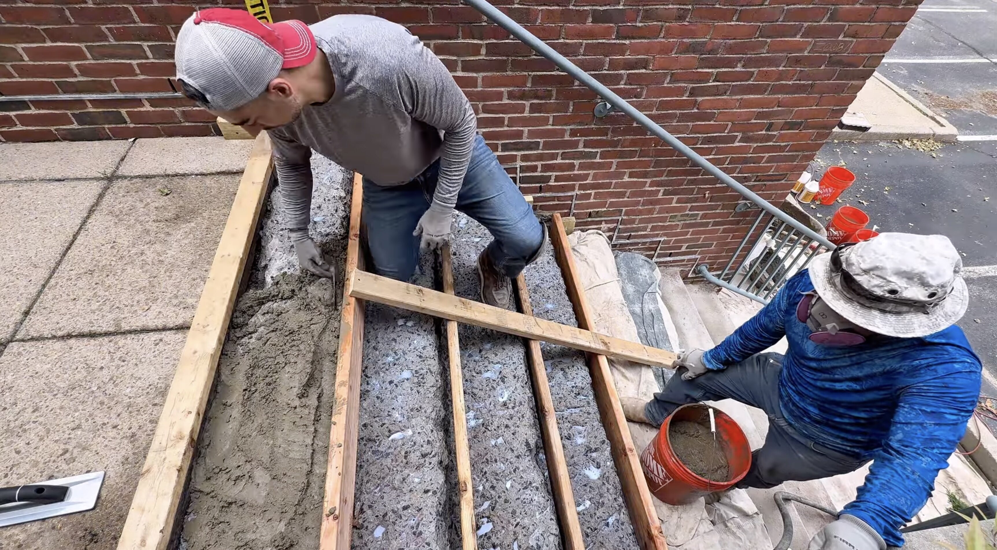 Contractors repairing and resurfacing exterior concrete stairs at a commercial building entrance