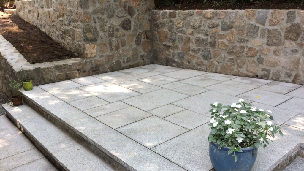 Custom stone patio installation with granite pavers and retaining wall in Boston, MA