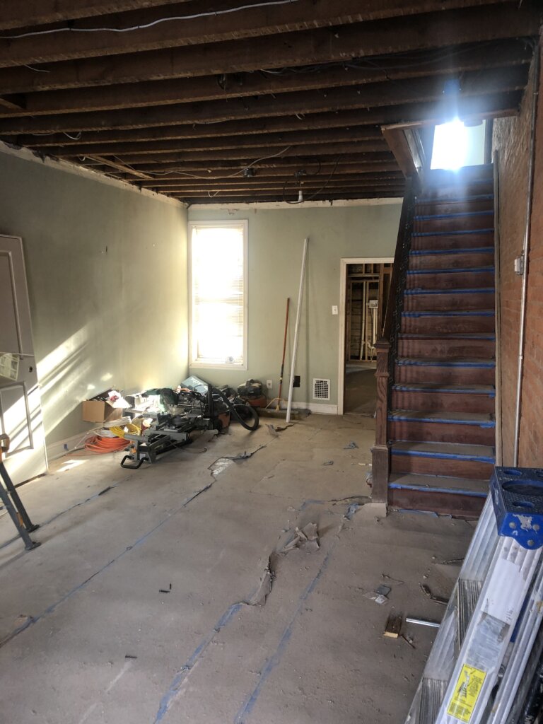 Philadelphia rowhome living room undergoing renovation with exposed drywall and construction materials.