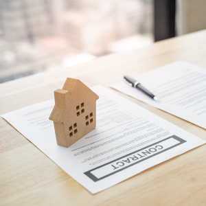 Wooden house model beside a loan document before closing
