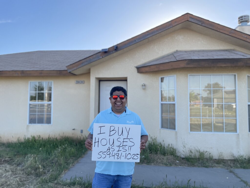 A Person holding a sign that says We Buy Houses Fresno As Is.