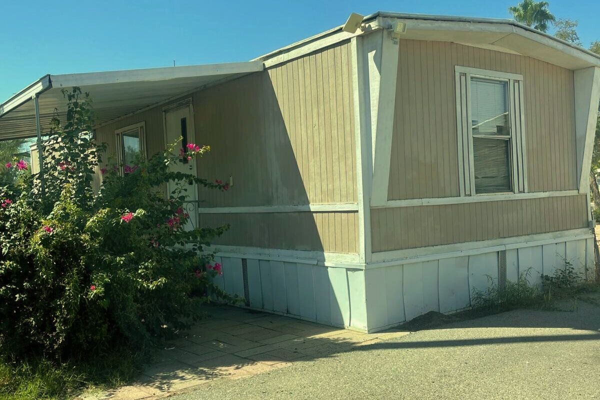 Single wide mobile home in Tucson community with side driveway and skirting