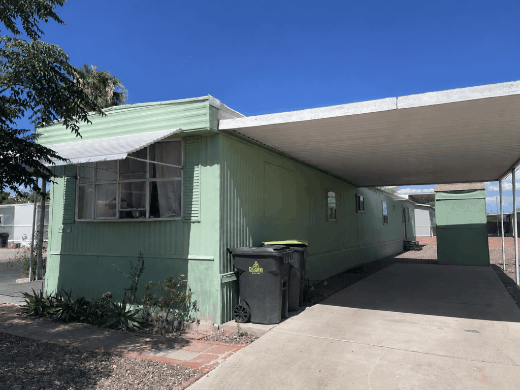 Green single-wide mobile home with covered carport and concrete driveway in Tucson Arizona