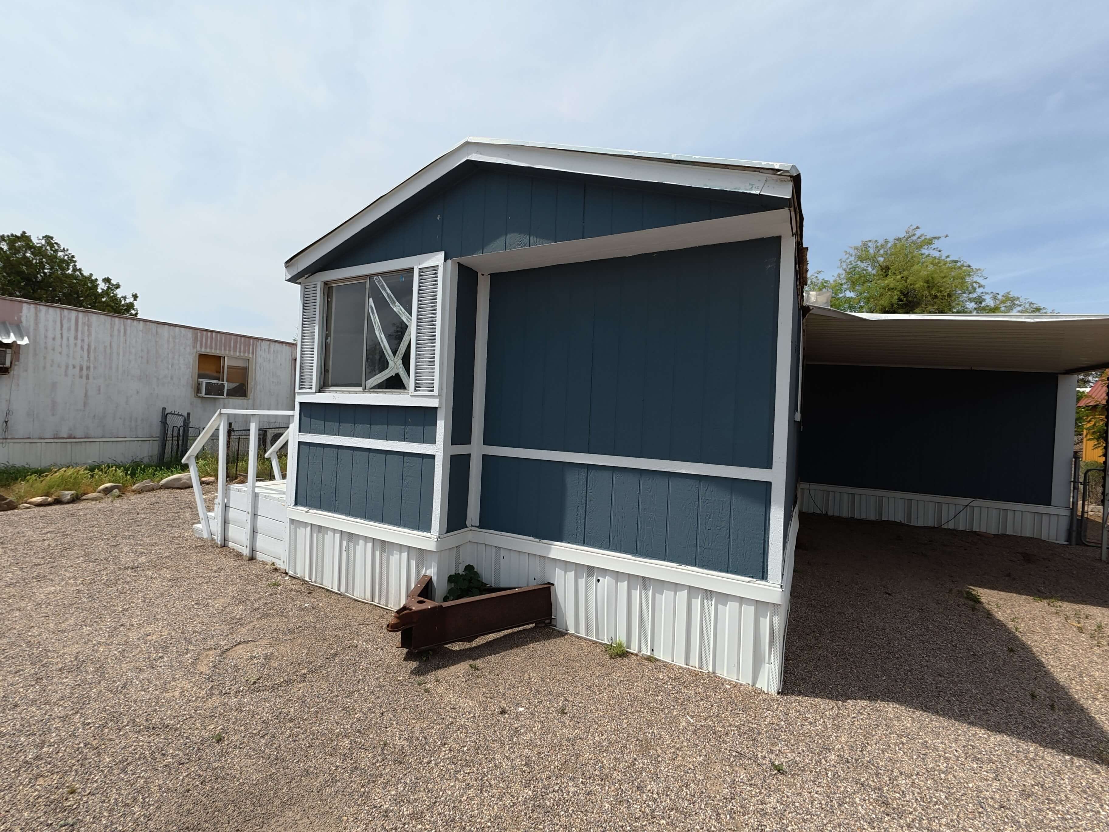 Blue single-wide mobile home with covered carport and front porch in Tucson Arizona