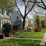 Suburban homes in Fredericksburg VA with landscaped lawns, blooming spring flowers, and mature trees along a quiet residential street