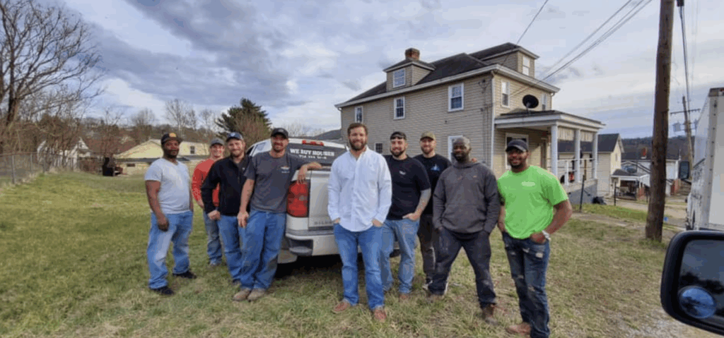 Team standing in front of a gray house next to a "We Buy Houses" truck