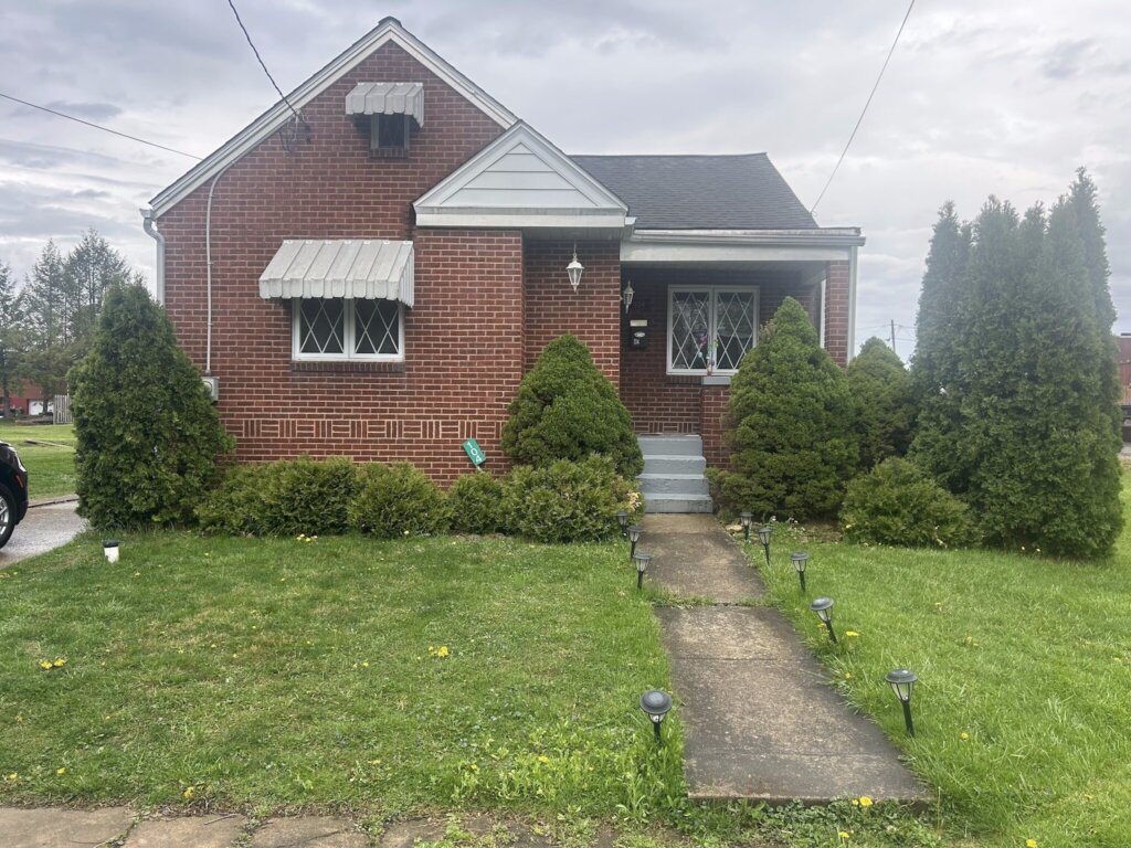 Brick house with white window awnings and a front walkway