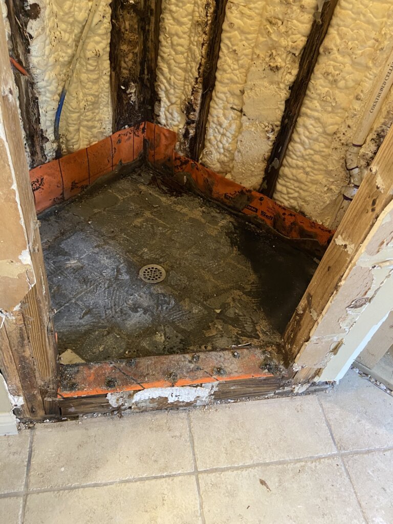 Rotted shower floor and walls with spray foam insulation exposed during bathroom renovation in Mandeville
