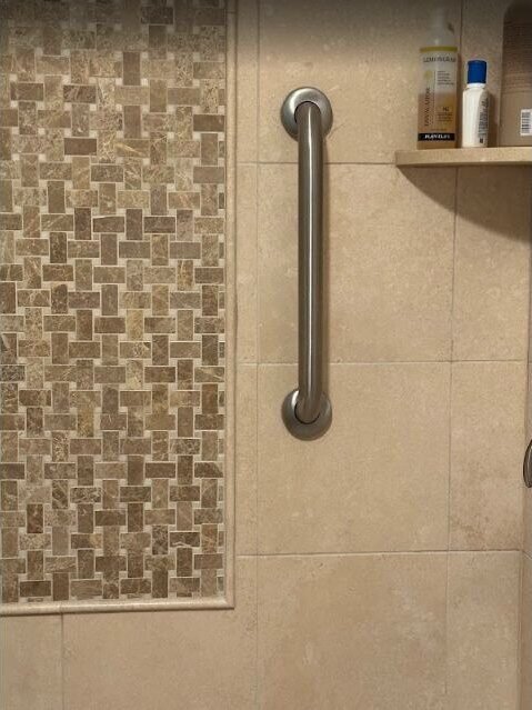 Accessible tiled shower detail with grab bar and mosaic accent