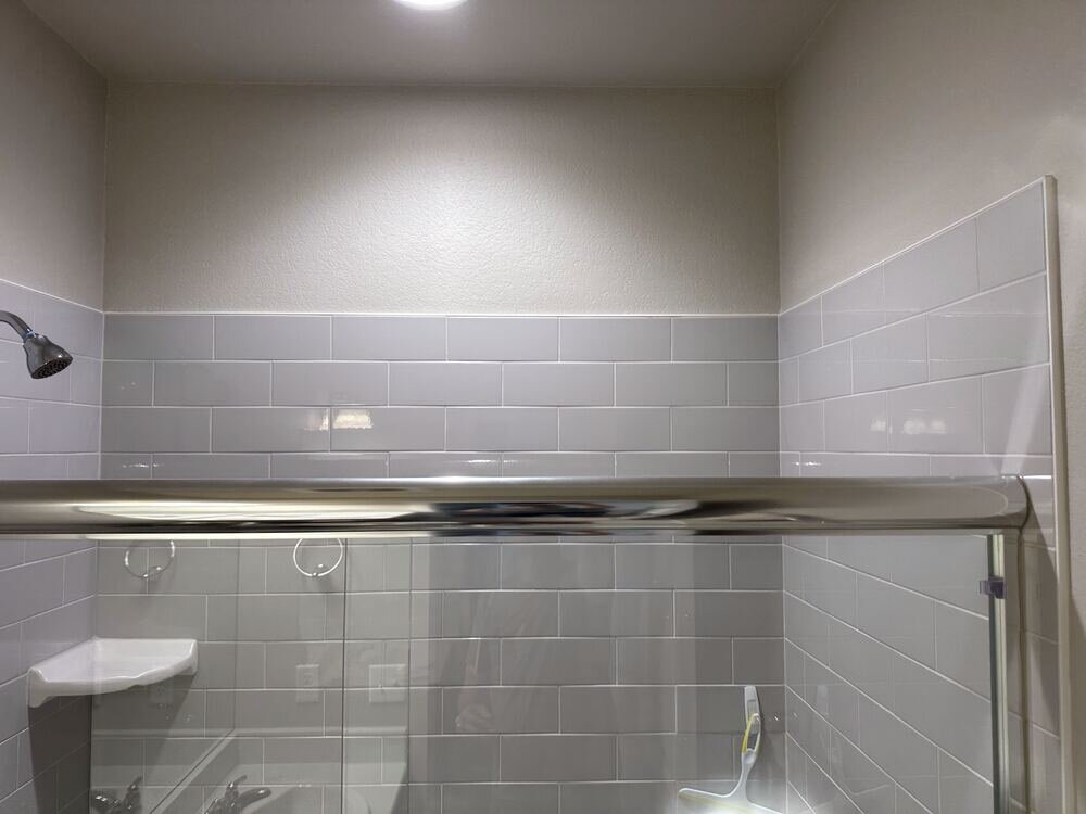 Detail of layered marble mosaic and subway tile shower wall, completed bathroom remodel by The Build Squad