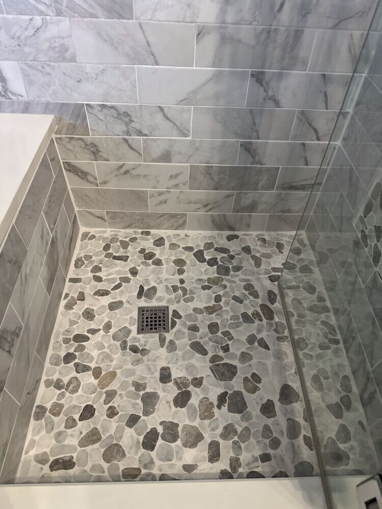 Pebble-stone shower floor detail, completed bathroom remodel by The Build Squad