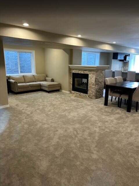 Finished basement lounge with recessed lighting and fireplace