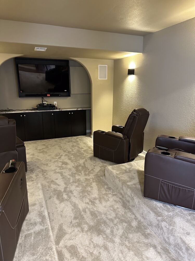 Finished home theater and entertainment room in a remodeled basement by The Build Squad