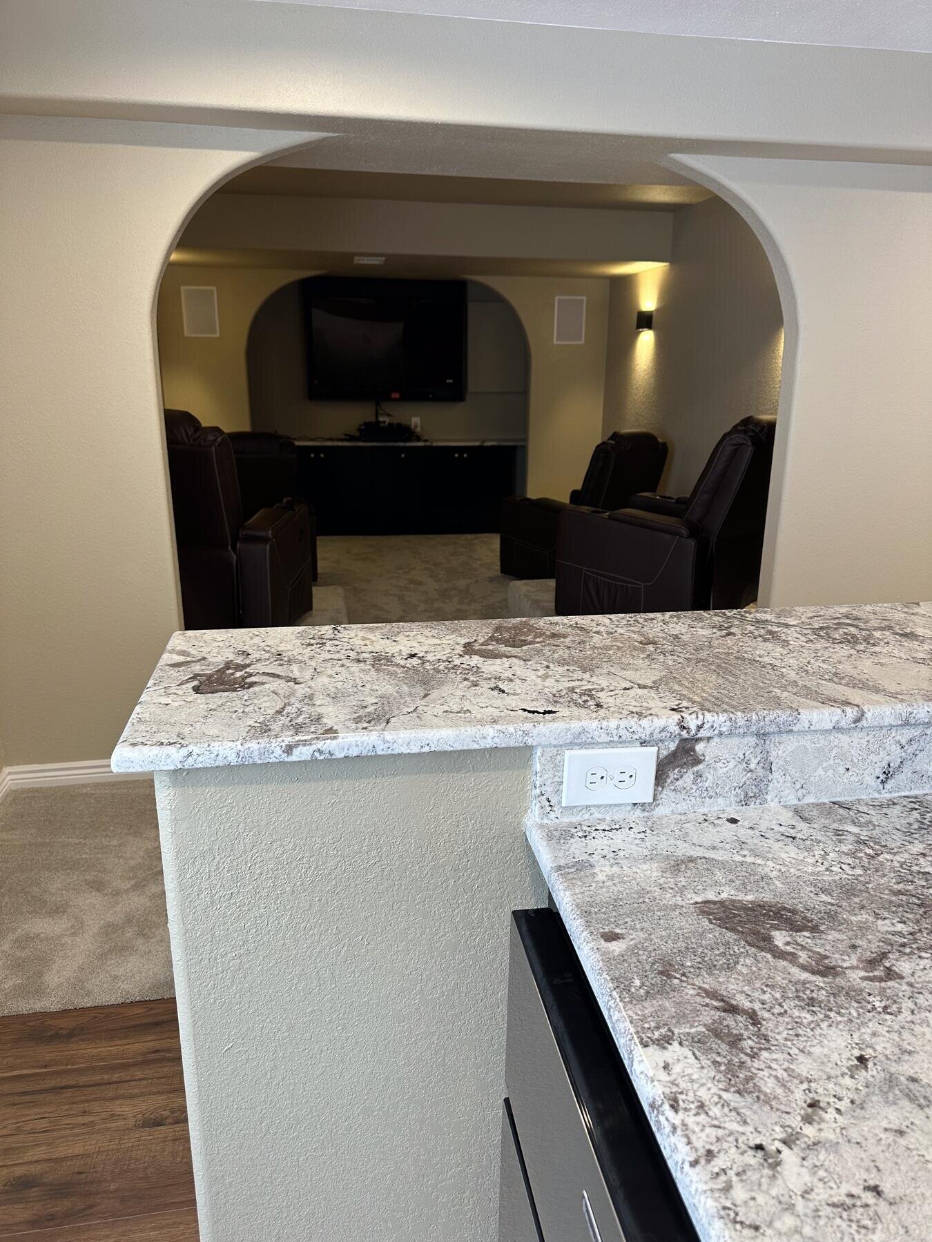 Finished basement home theater with an adjoining granite wet bar, completed remodel by The Build Squad