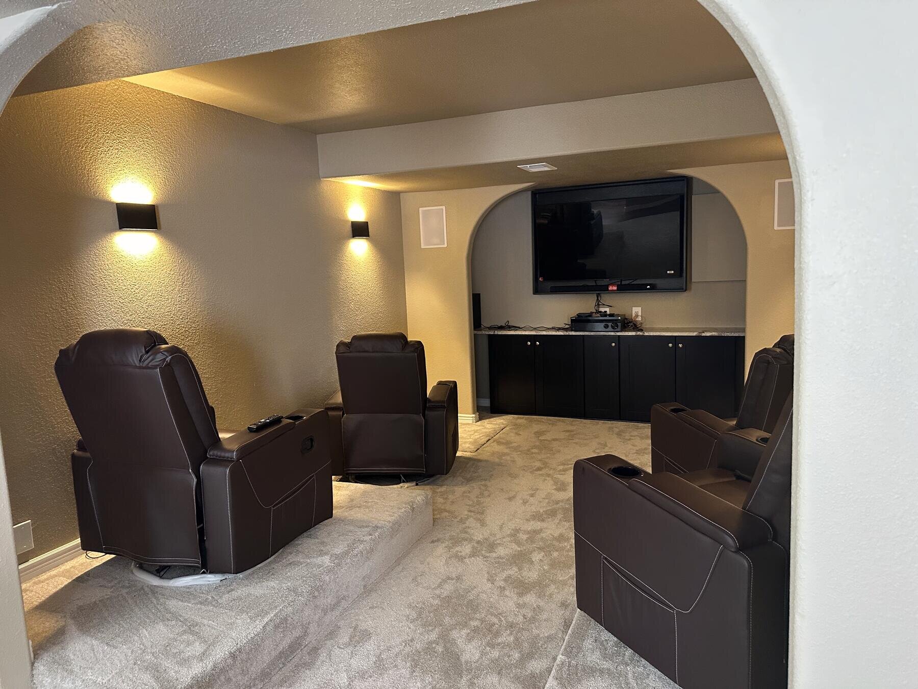 Finished basement home theater with leather recliners and a mounted TV, completed remodel by The Build Squad