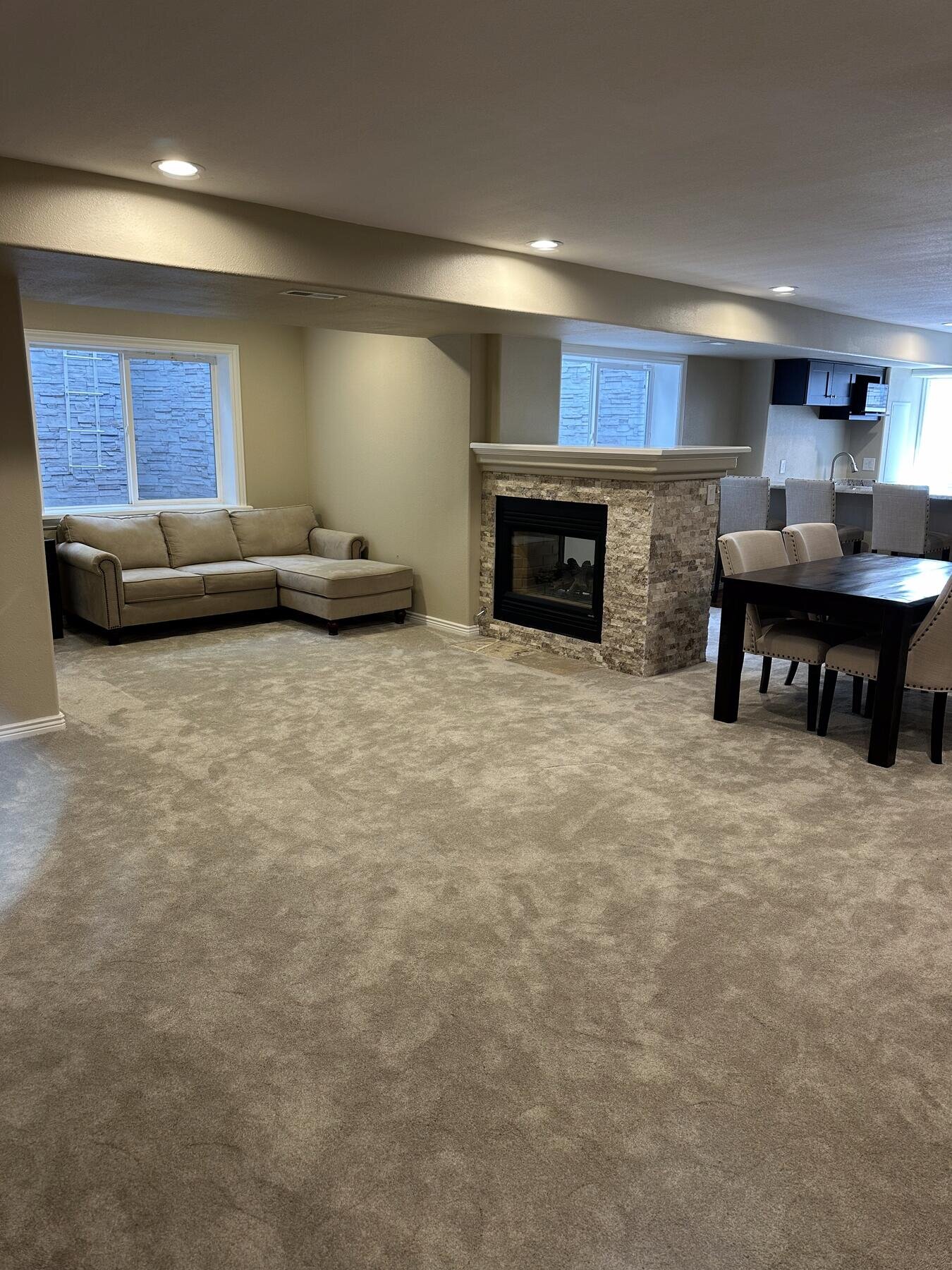 Finished basement living and dining area with a sectional sofa and dining table, completed remodel by The Build Squad