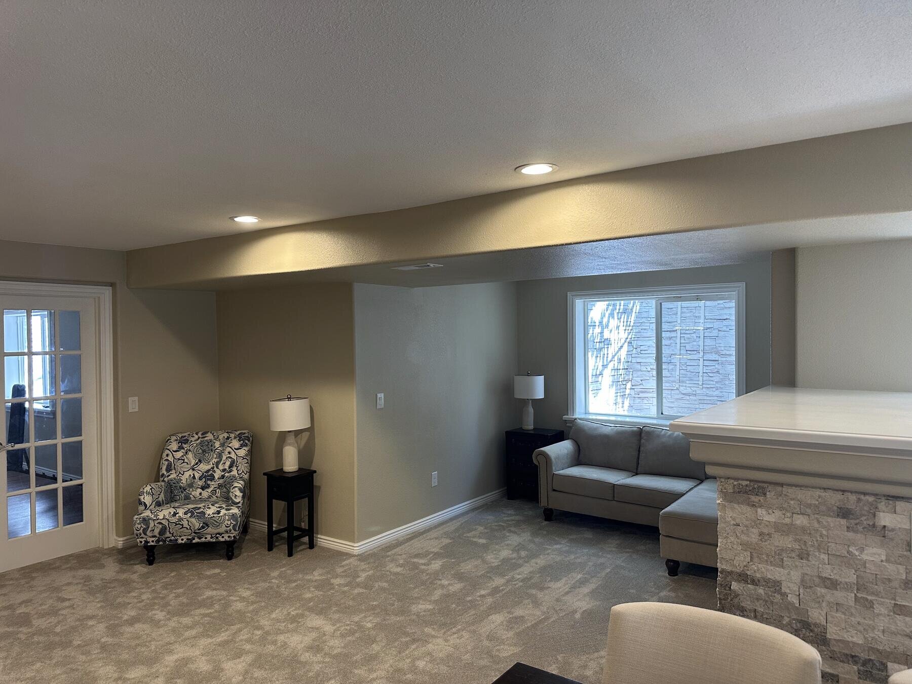 Completed basement living room remodel featuring a stone fireplace accent wall
