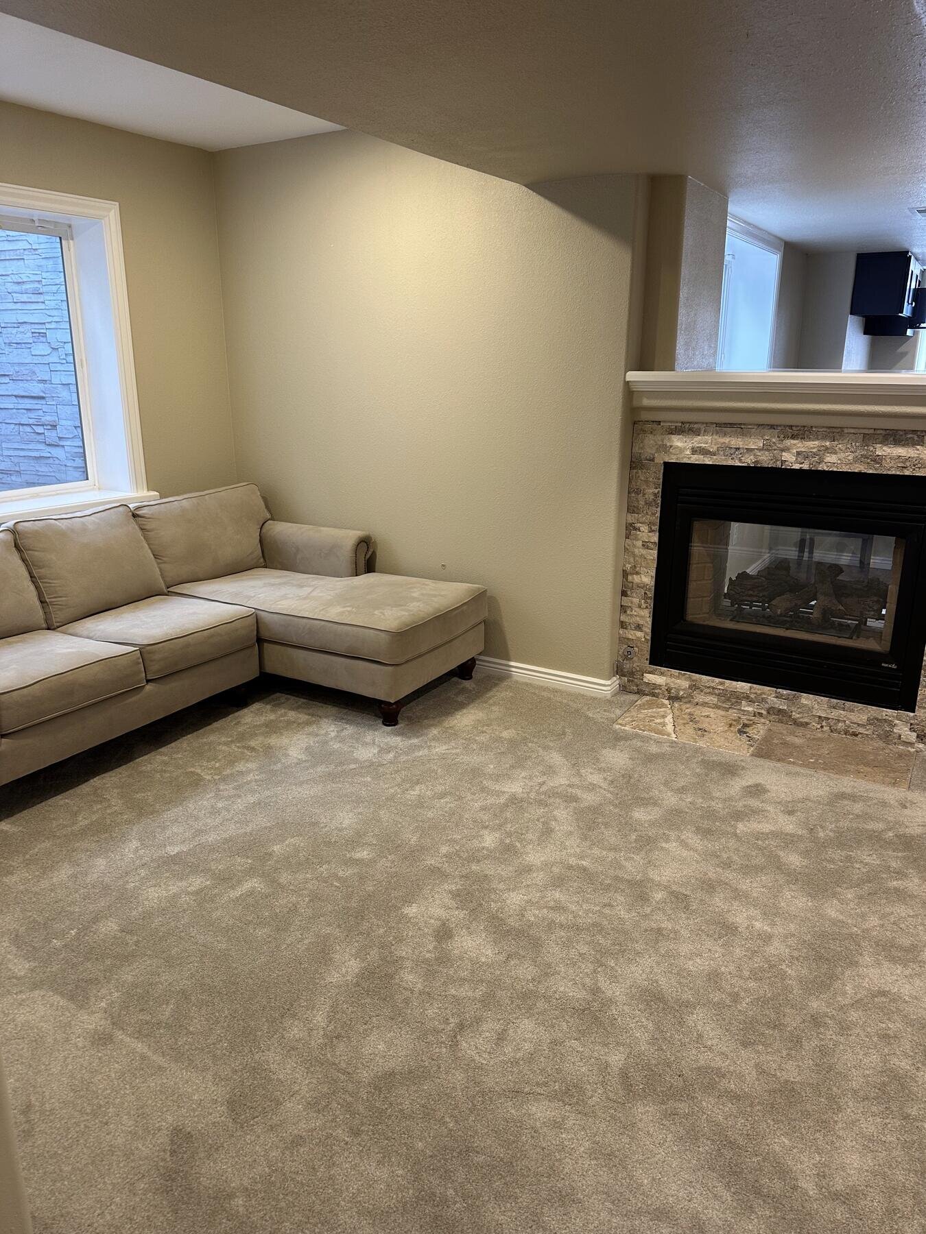 Detail of a stone fireplace surround with a mounted TV in a finished basement, completed remodel by The Build Squad
