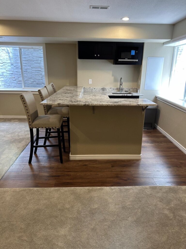 Detail of finished wet bar cabinetry and a mini fridge in a remodeled basement by The Build Squad