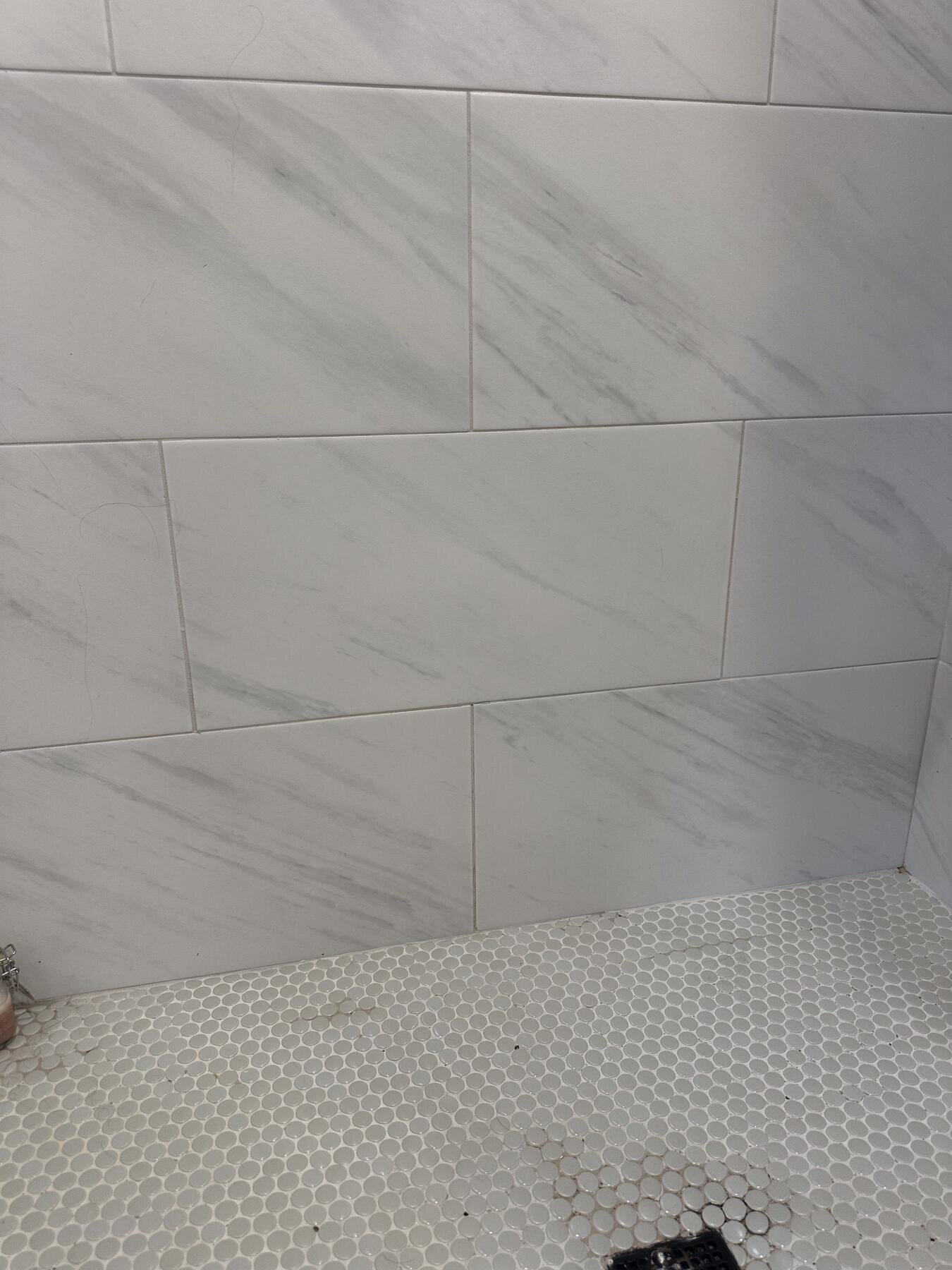 Finished marble-tile shower with a built-in bench and pebble floor, completed bathroom remodel by The Build Squad
