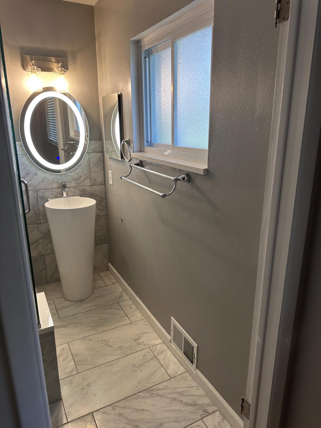 Finished powder room with a pedestal-style sink and tile floor, completed remodel by The Build Squad