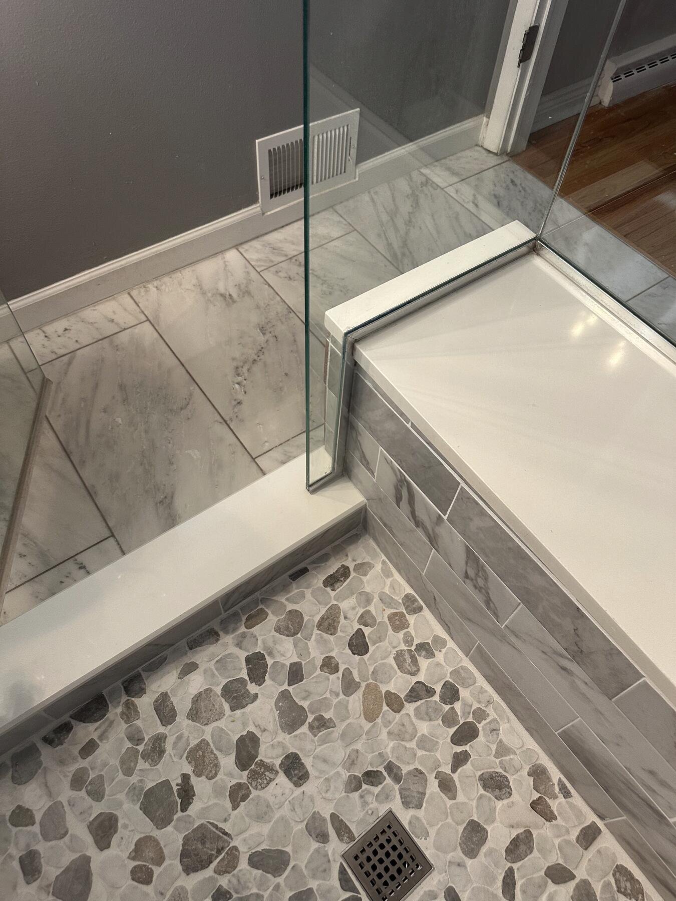Detail of a tiled shower bench and glass enclosure, completed bathroom remodel by The Build Squad