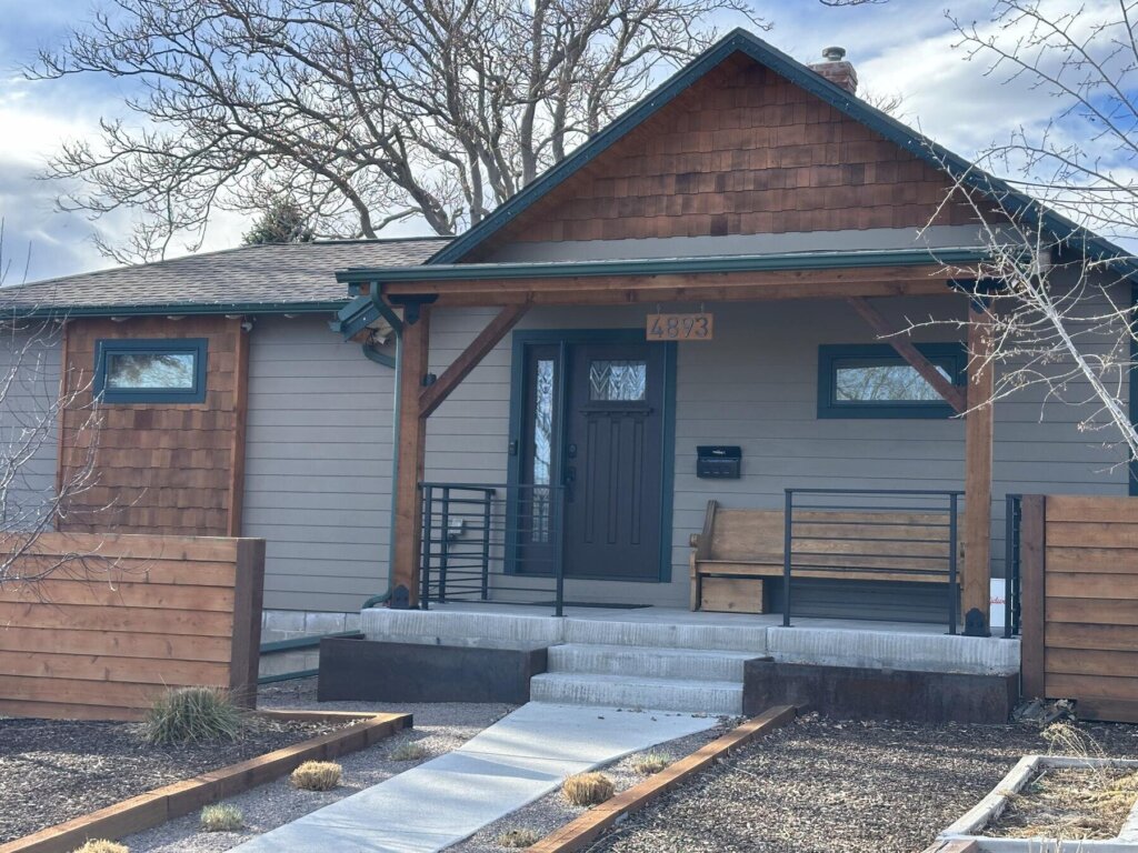 Finished concrete walkway and steps with a wood-beam front porch accent, completed exterior remodel by The Build Squad