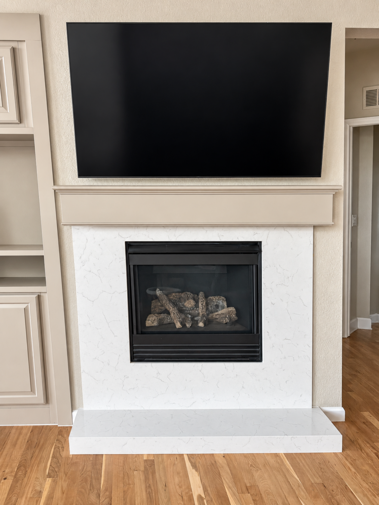 Gas fireplace with white quartz surround and wall-mounted television