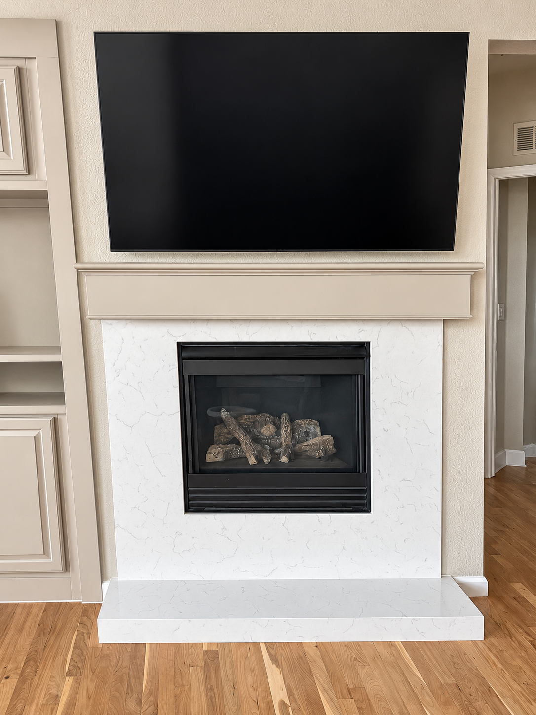 Gas fireplace with white quartz surround and wall-mounted television