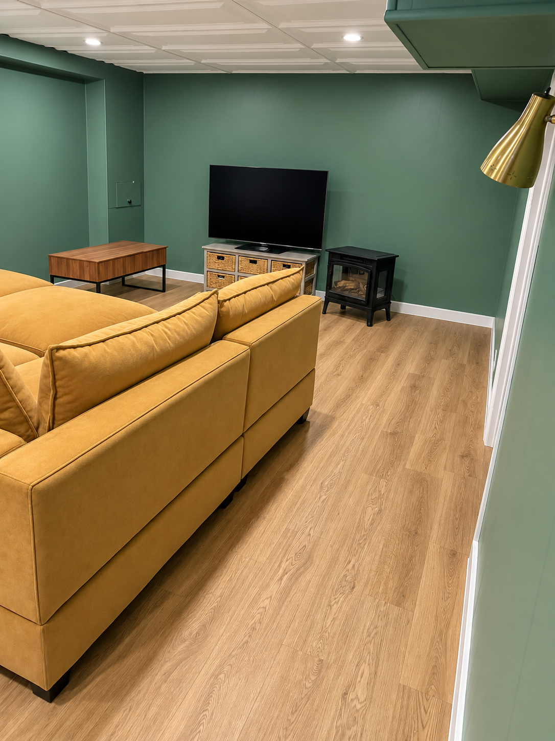 Basement family room with green walls, sectional sofa, and electric fireplace