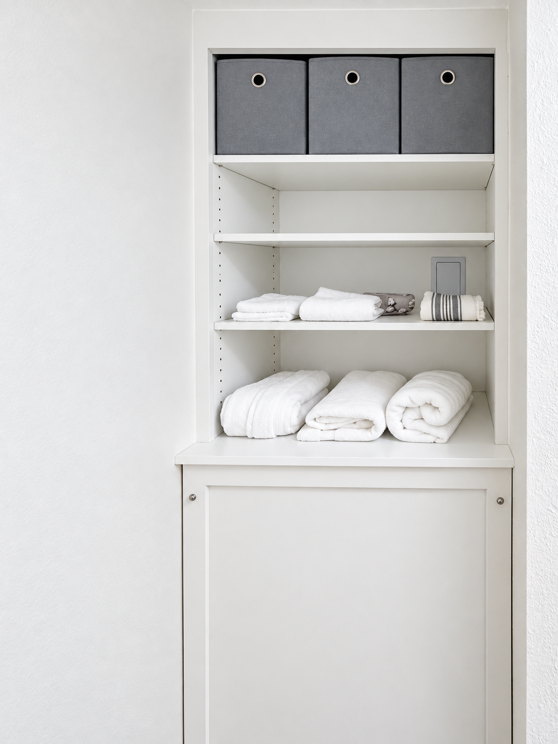 Built-in linen storage cabinet with open shelving and folded towels