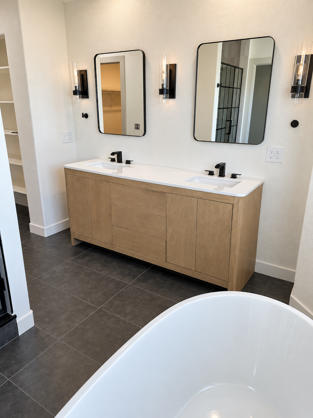 Bathroom with wood vanity, black fixtures, and freestanding tub, front view