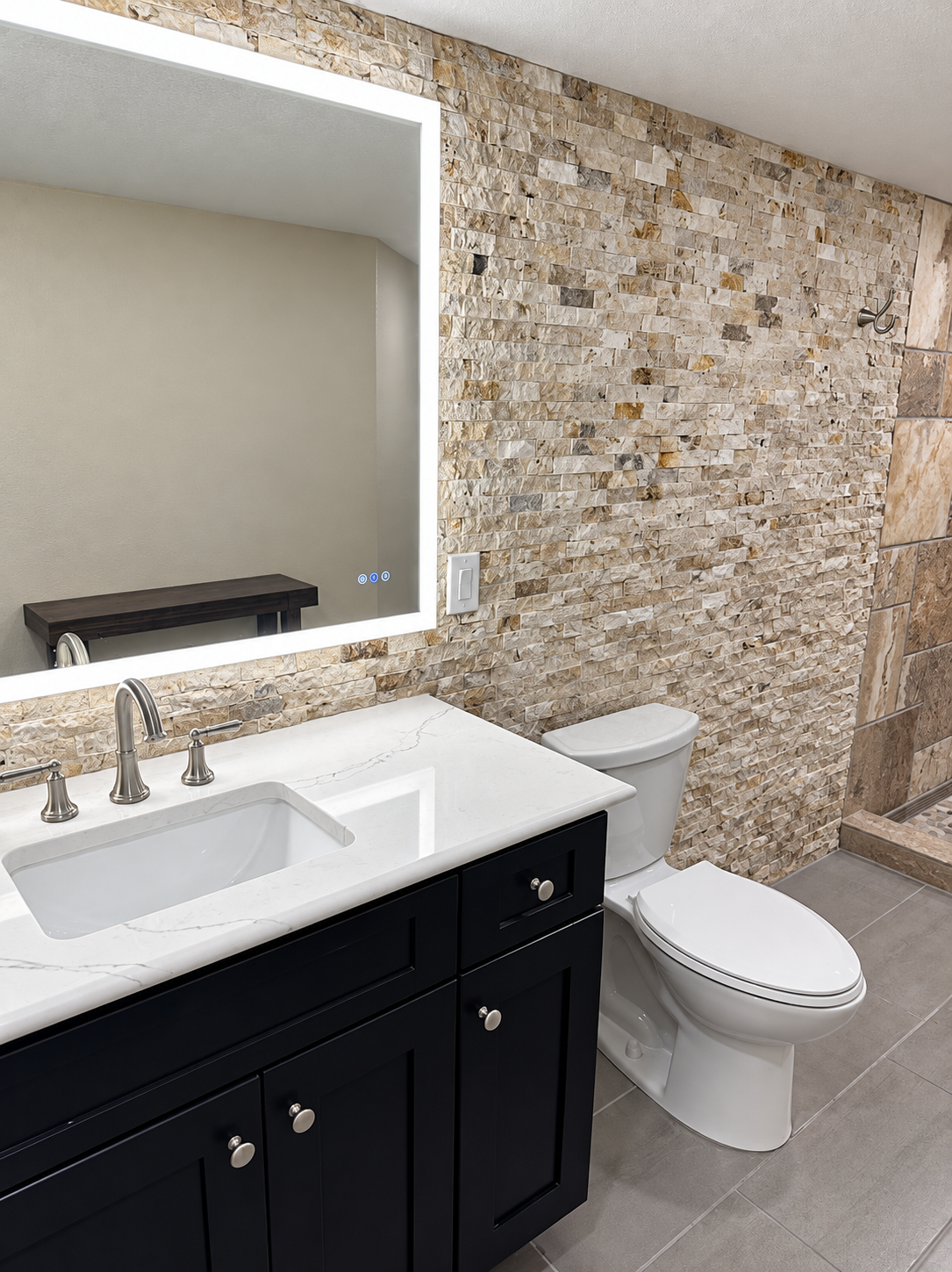 Bathroom vanity with dark cabinetry and stacked-stone accent wall
