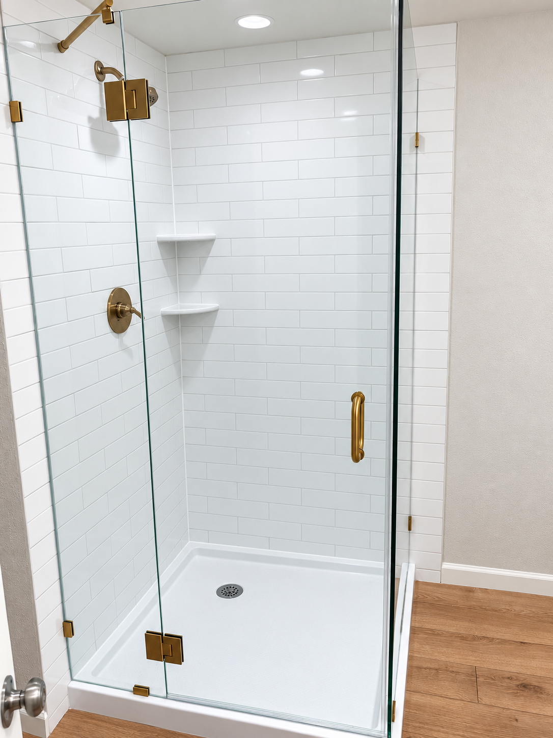 Glass-enclosed shower with white subway tile and brass fixtures