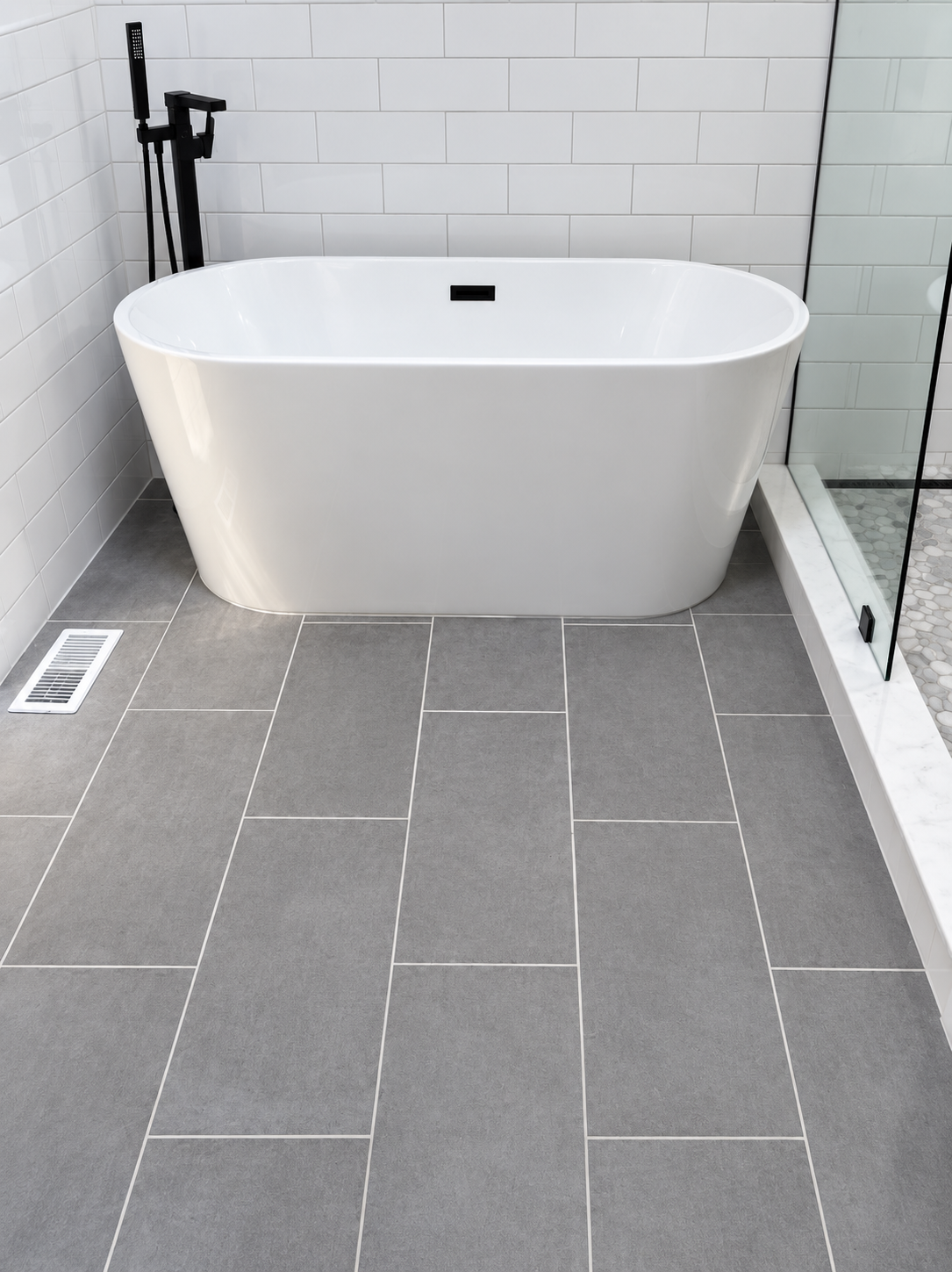 Freestanding white tub with black floor-mount filler, close view