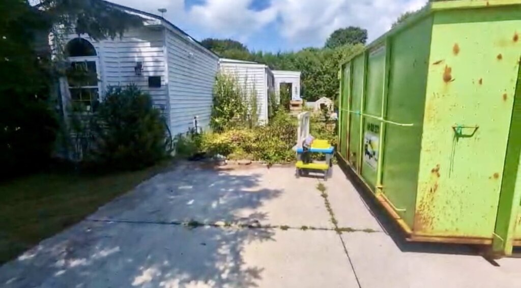 house with repairs needed with a construction bin outside