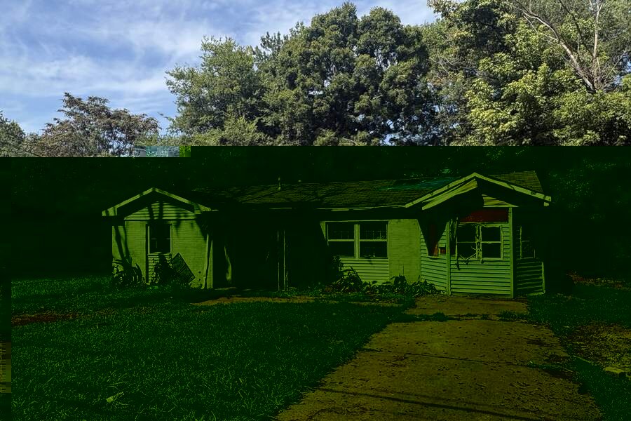 Fire damaged house with blue tarp roof and boarded windows in Huntsville, AL