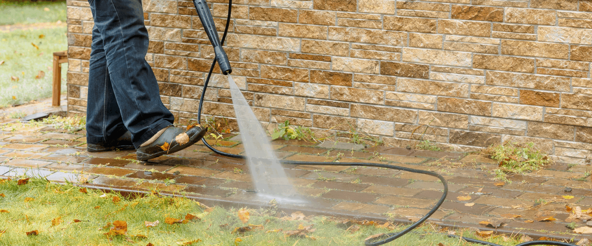 Worker pressure washing walkway