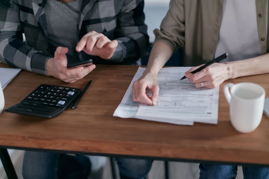 A couple sitting at a wood desk working through tax forms