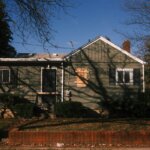 Weathered green Flint Michigan house boarded window — foreclosure sheriff sale cash buyer Genesee County