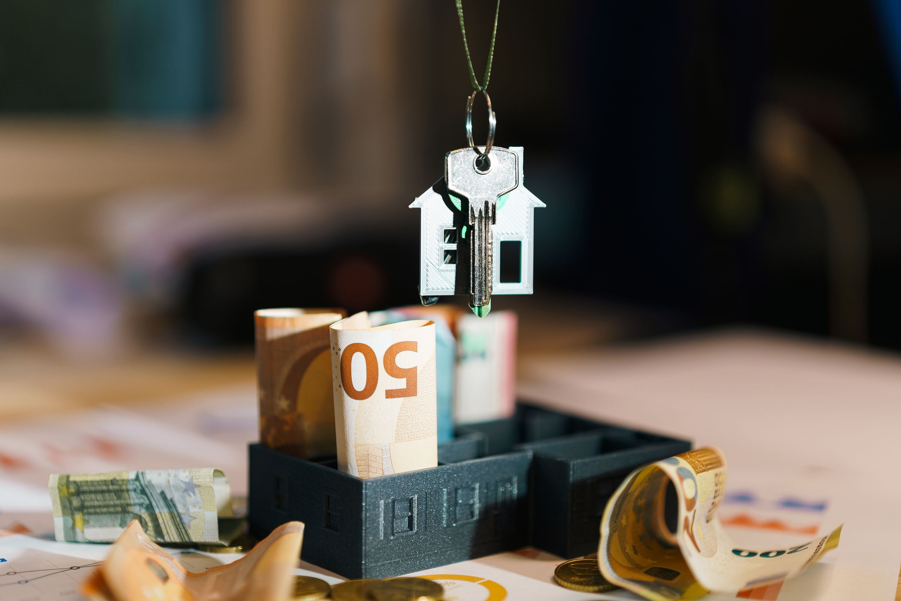 Stack of cash next to a house key, representing the concept of a cash home buyer