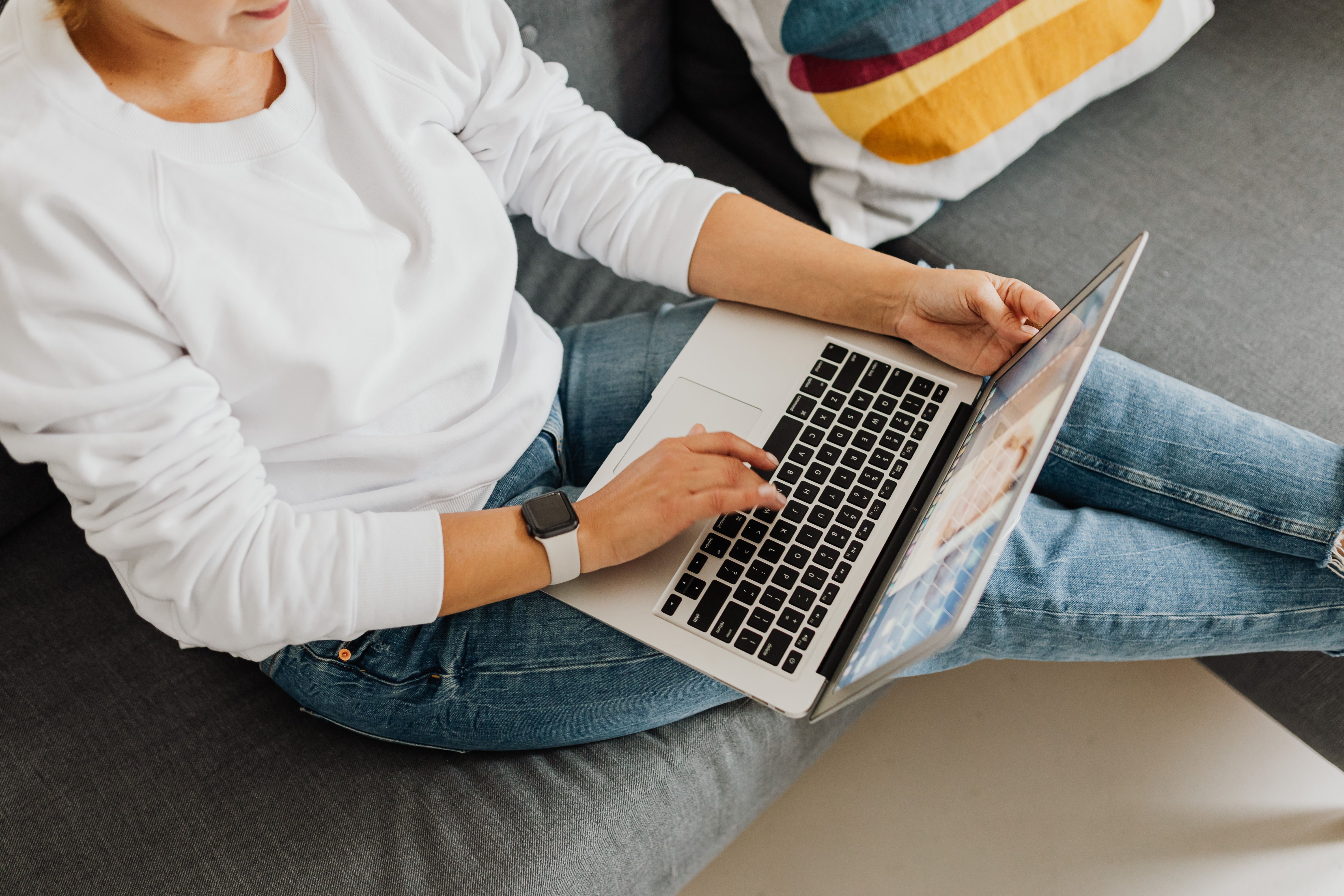 Person using a laptop at a kitchen table, representing requesting a cash offer online