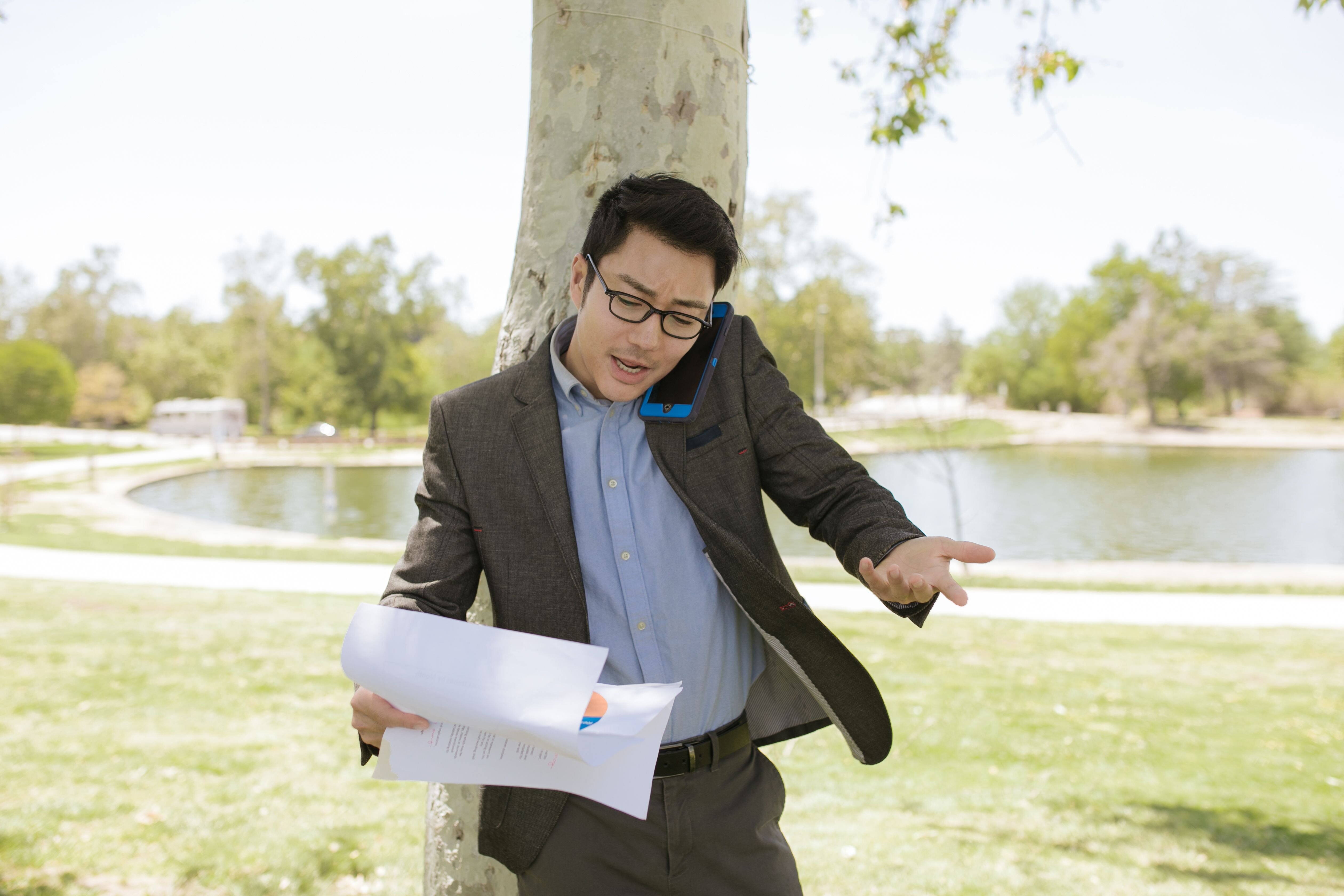 Person on the phone reviewing paperwork at a desk, representing an urgent call to stop foreclosure