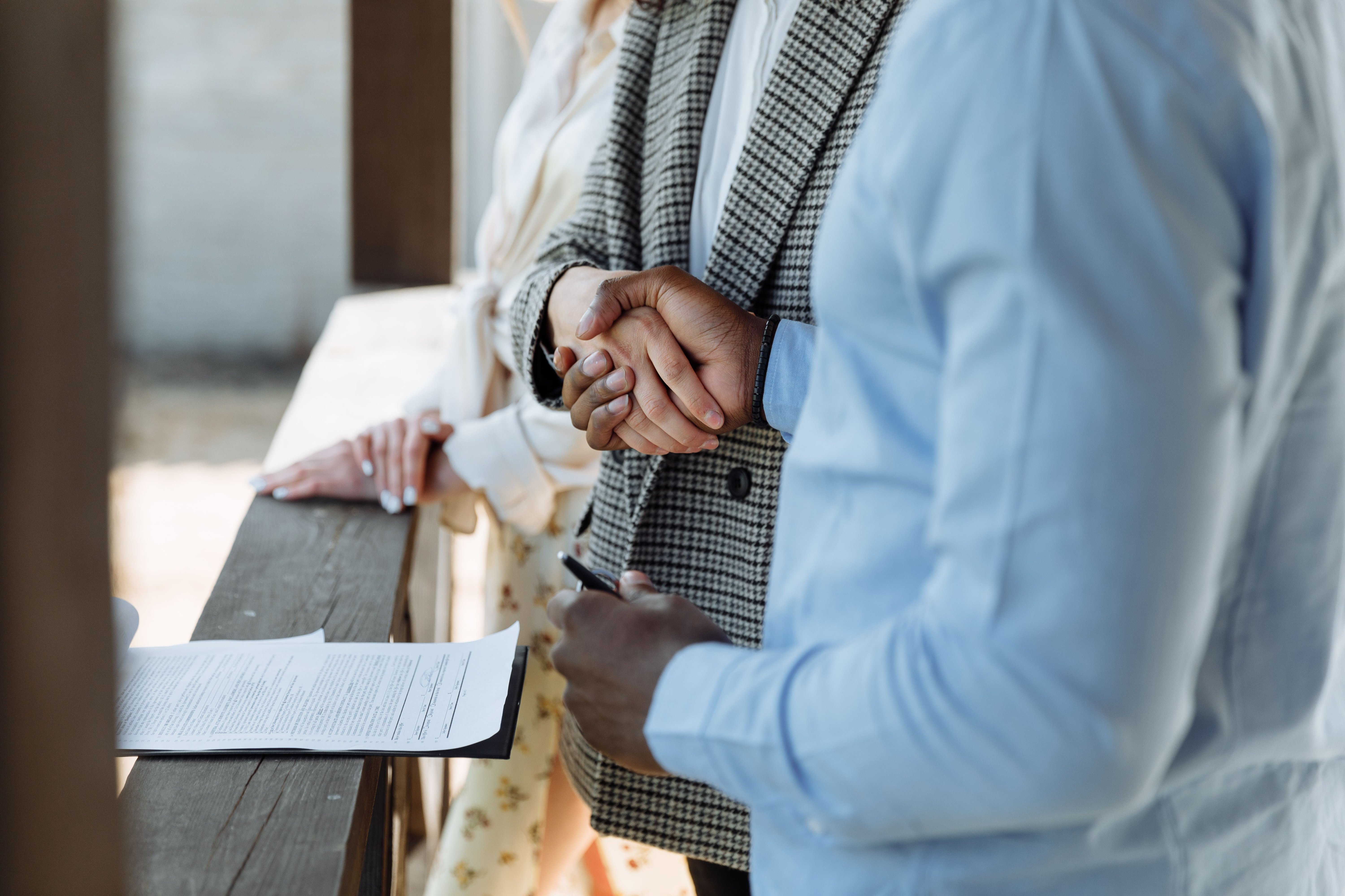 Two people shaking hands over a real estate contract, representing the home-selling process with a cash buyer