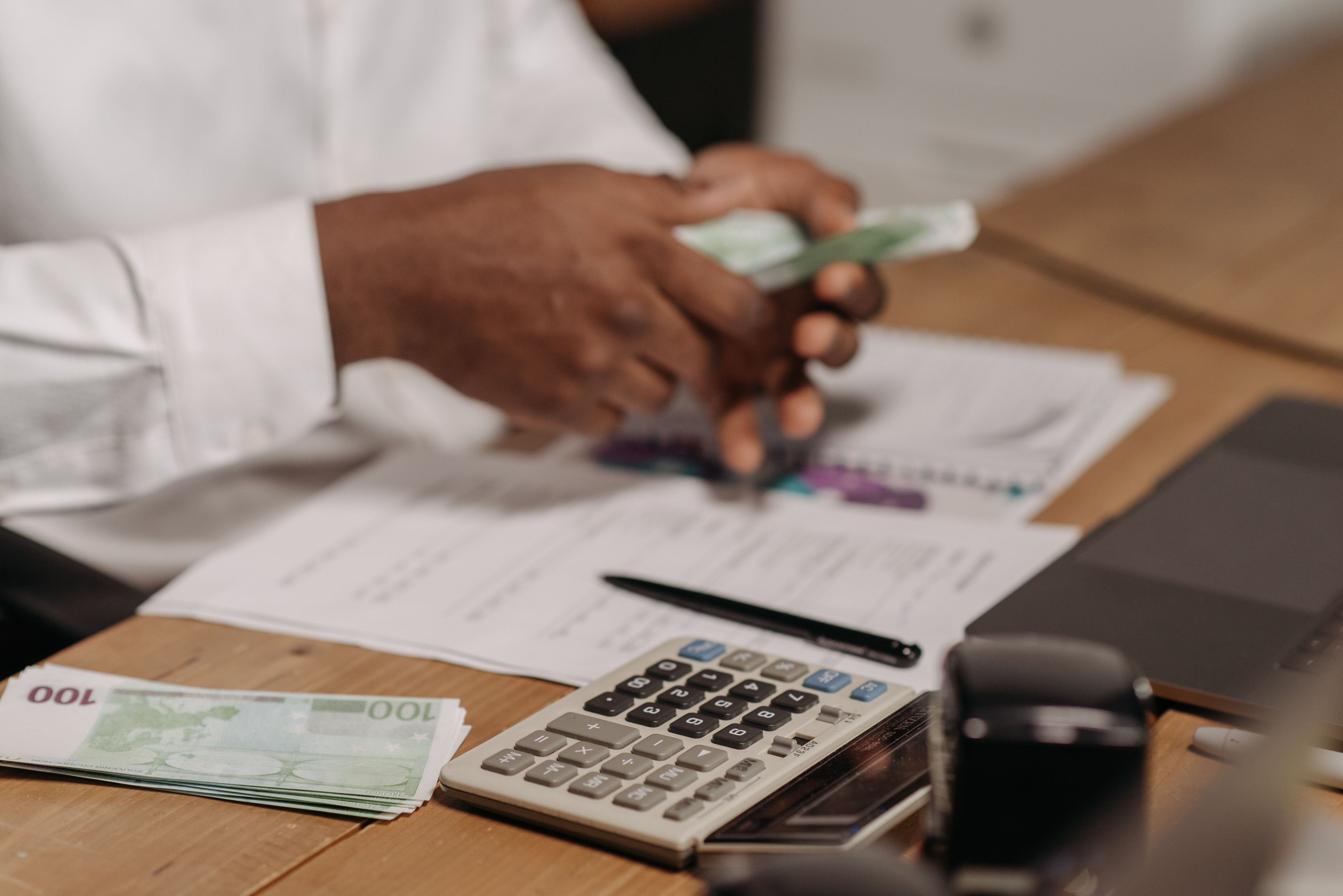 A calculator resting on paperwork with cash, representing calculating closing costs on a home sale