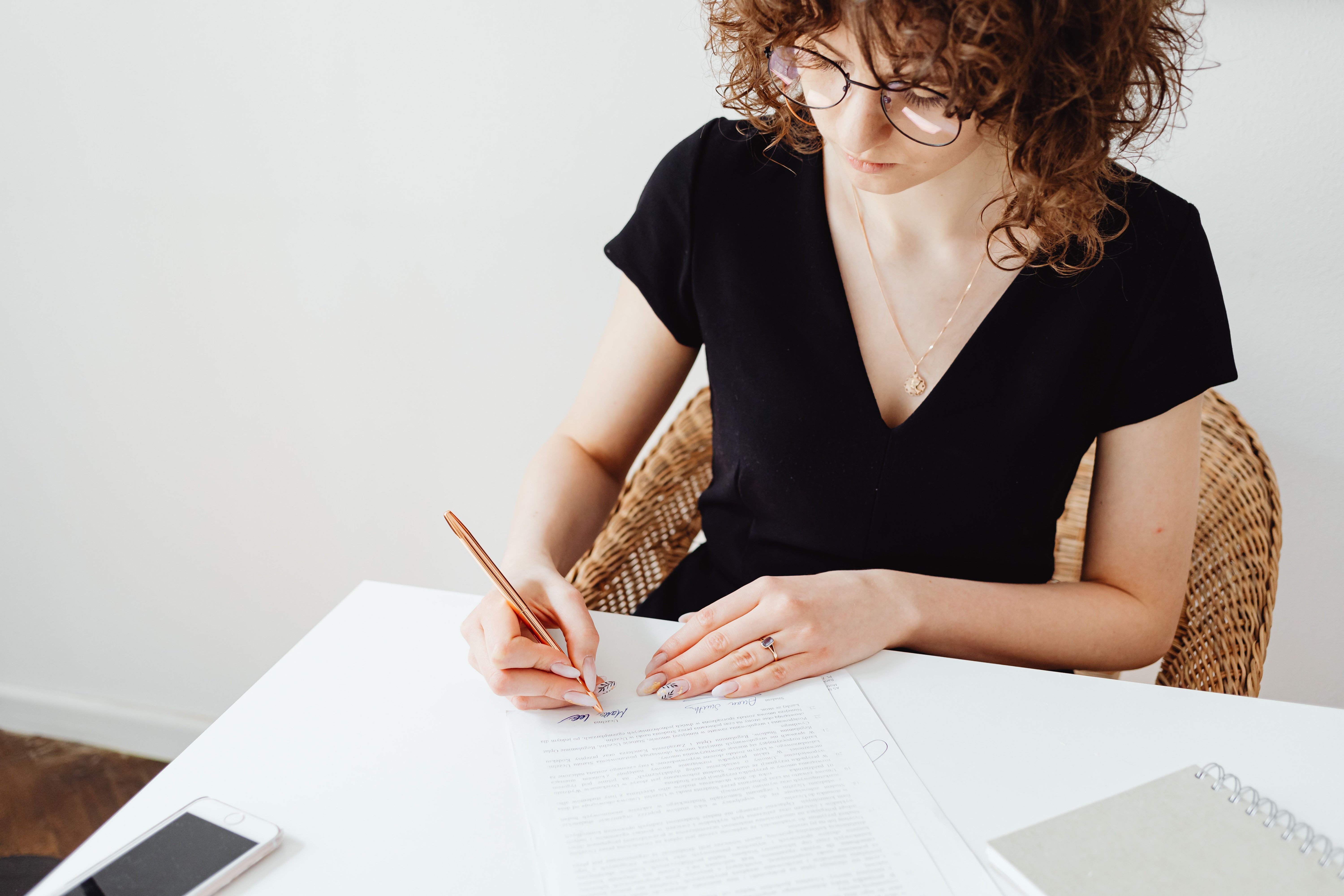 A person signing a document alone at a table, representing a question about selling a home without a spouse's consent