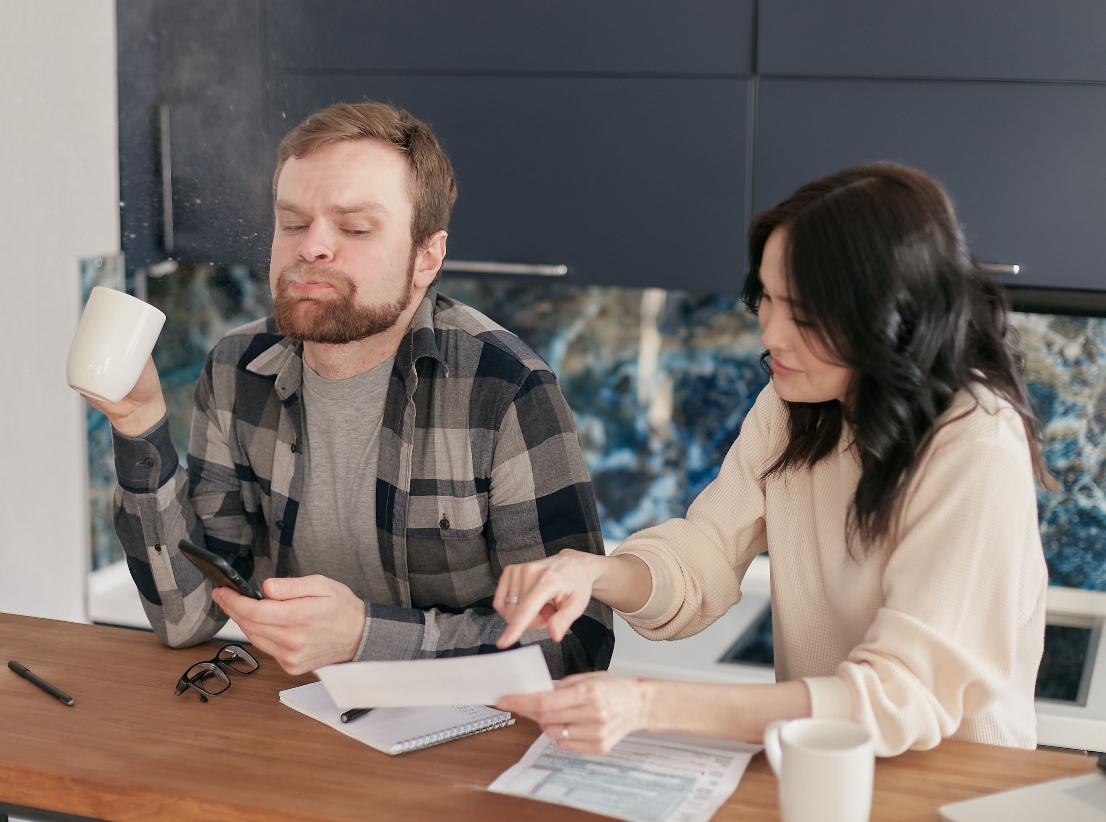 A San Antonio homeowner comparing paperwork for different home-selling options at a kitchen table