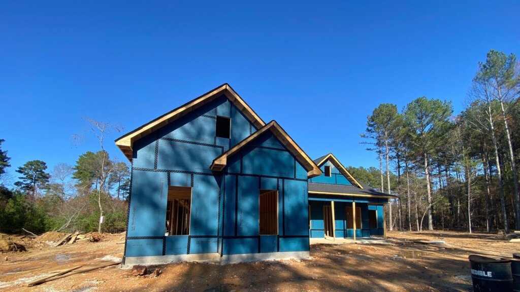 Custom home under construction featuring exterior framing, weather-resistant barrier, and modern farmhouse architecture in Huntsville, Alabama.
