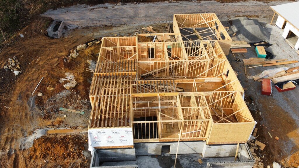 Structural wood pillars with vaulted ceiling structure and concrete foundation slab for a new custom home. 