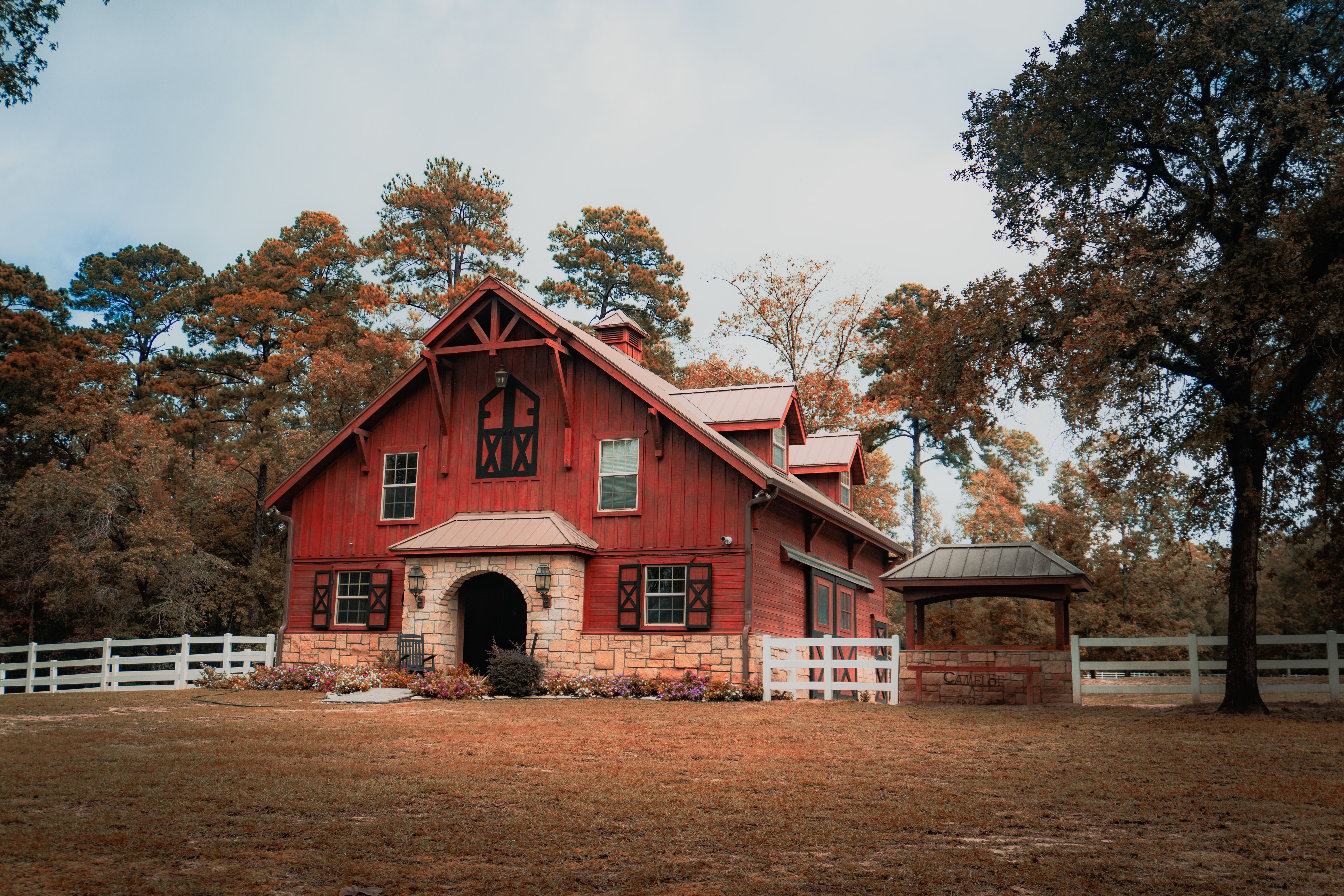 Rustic red timber-frame barn home with natural stone archway entry and custom exterior woodwork built in North Alabama.